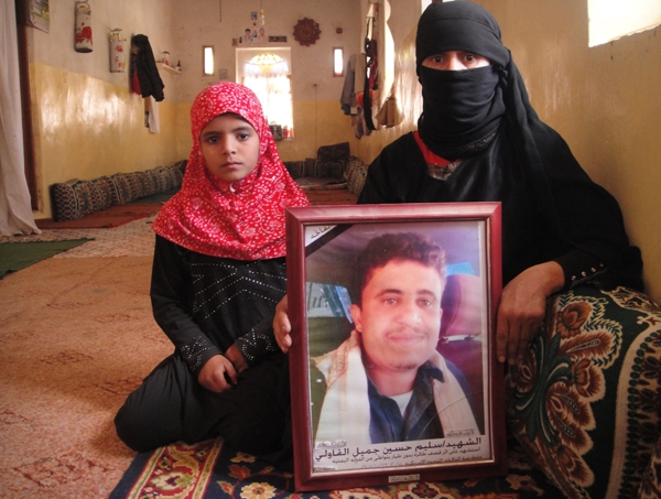 Oum Salim sits in her home majlis in Khawlan holding a photo of her late son Salim Hussein Ahmed Jamil, her daughter Asmaa, 7, by her side. /By Vivian Salama